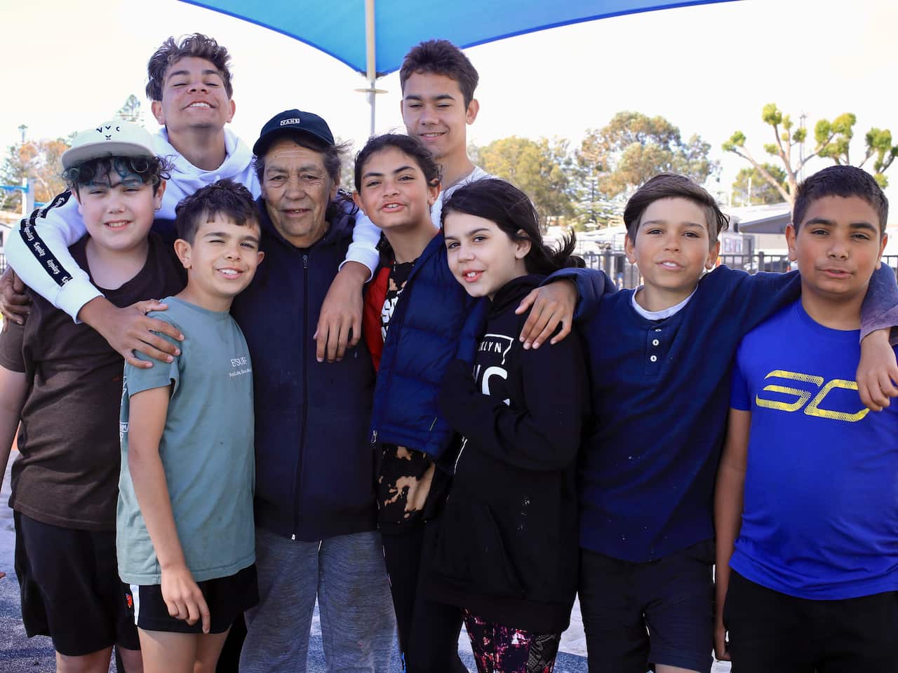 Sue Haseldine standing outside surrounded by eight of her grandchildren.