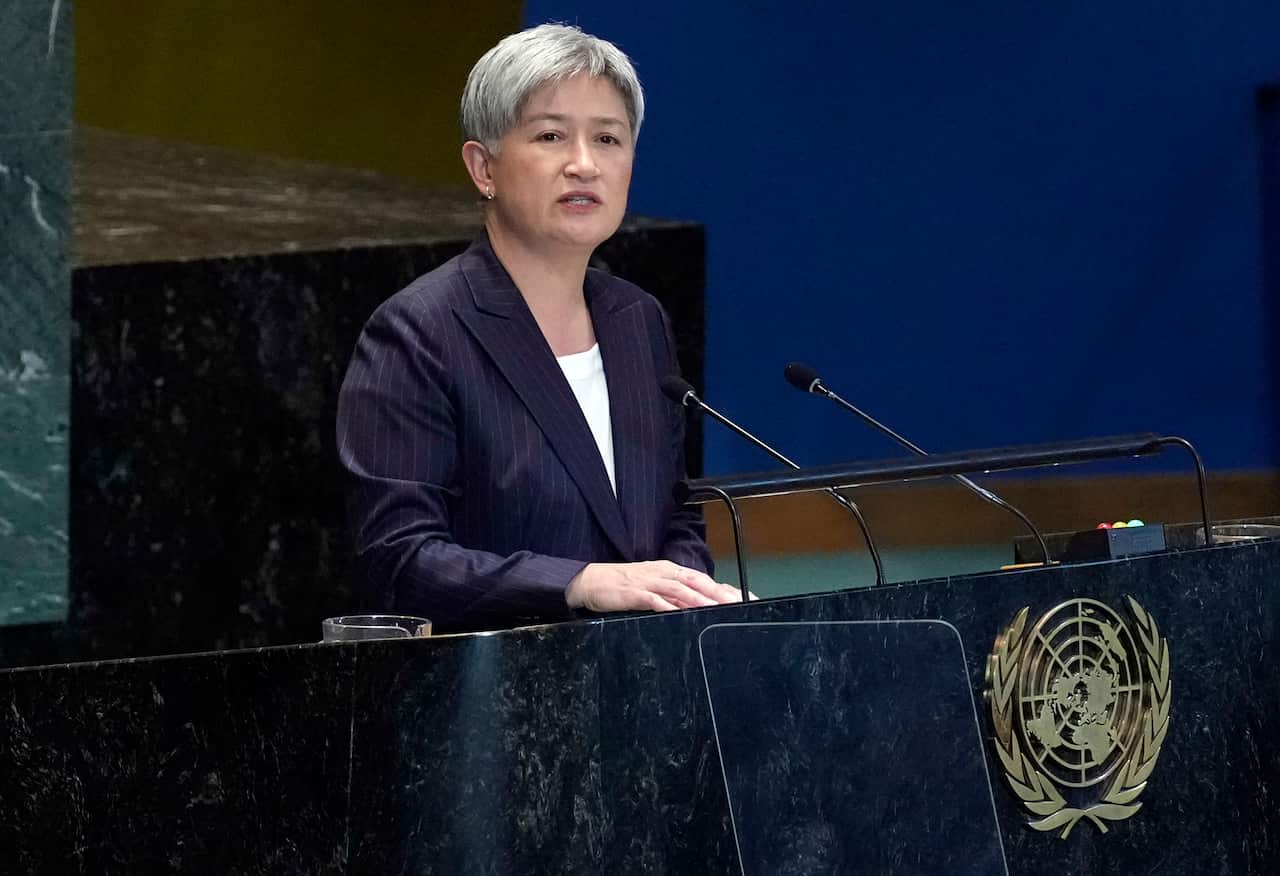 A woman speaking at a lectern with the United Nations crest.