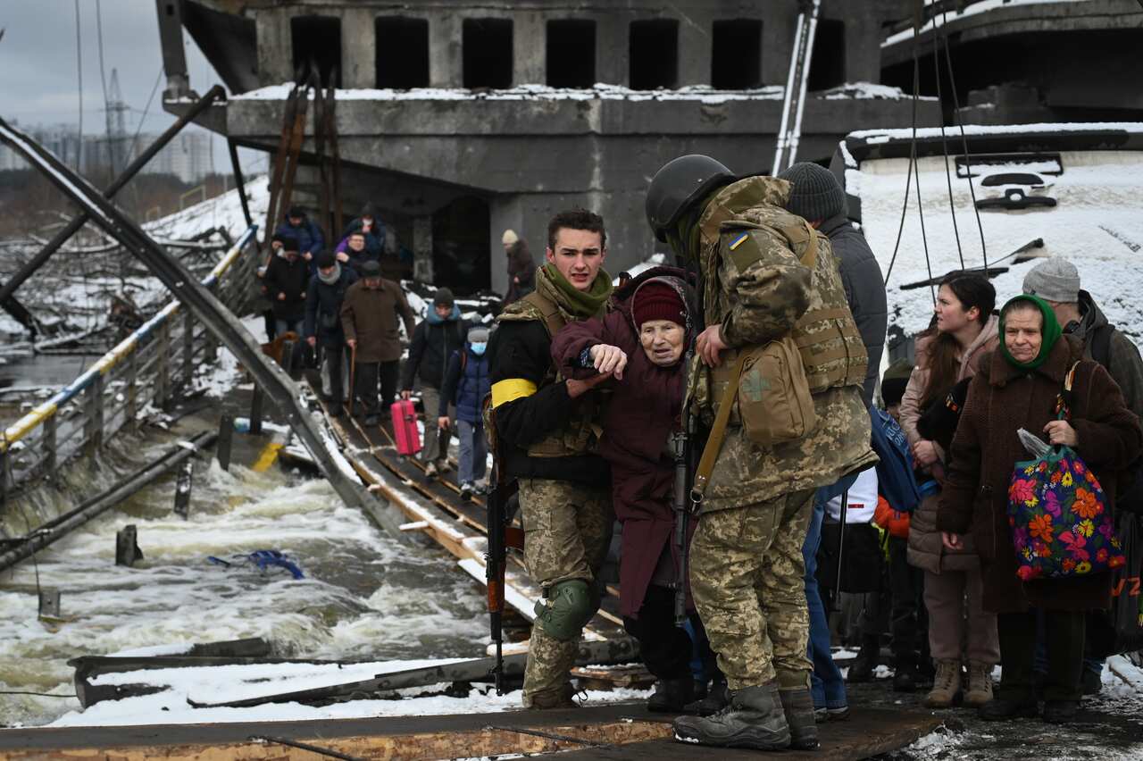 Two Ukrainian troops are seen assisting an older person during an evacuation effort.