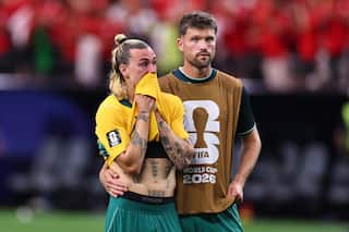 A football player in a green and yellow jersey is comforted by a teammate