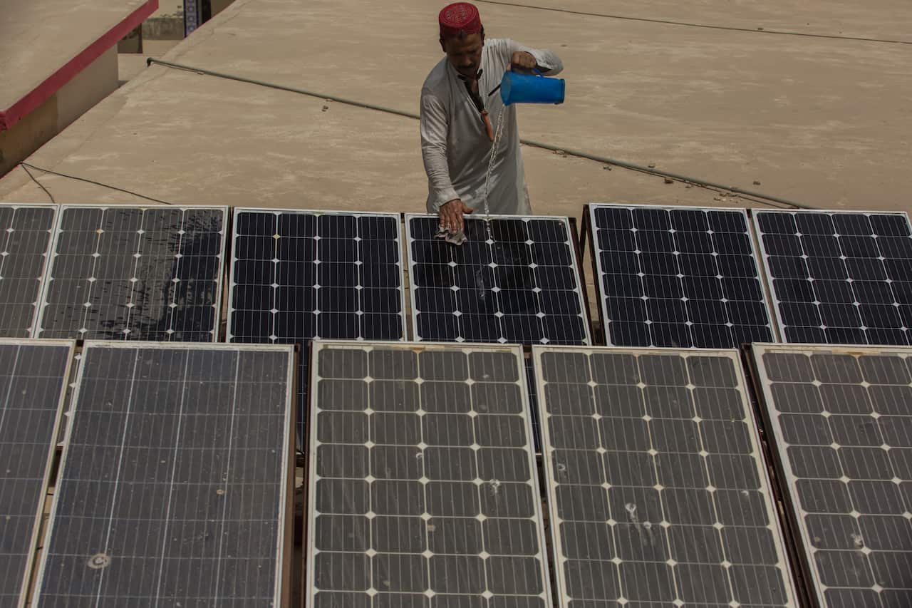 A Pakistani man pours water over solar panels in Jacobabad, Pakistan, in 2022.