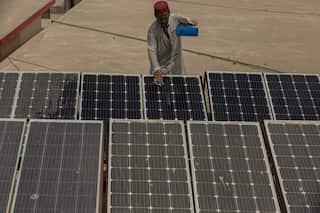 A Pakistani man pours water over solar panels in Jacobabad, Pakistan, in 2022.