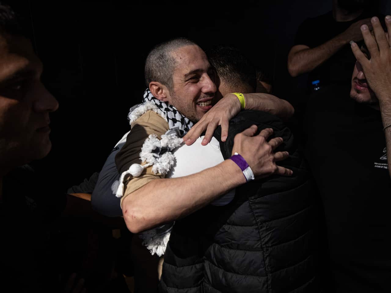 Two people joyfully embrace, one wearing a keffiyeh