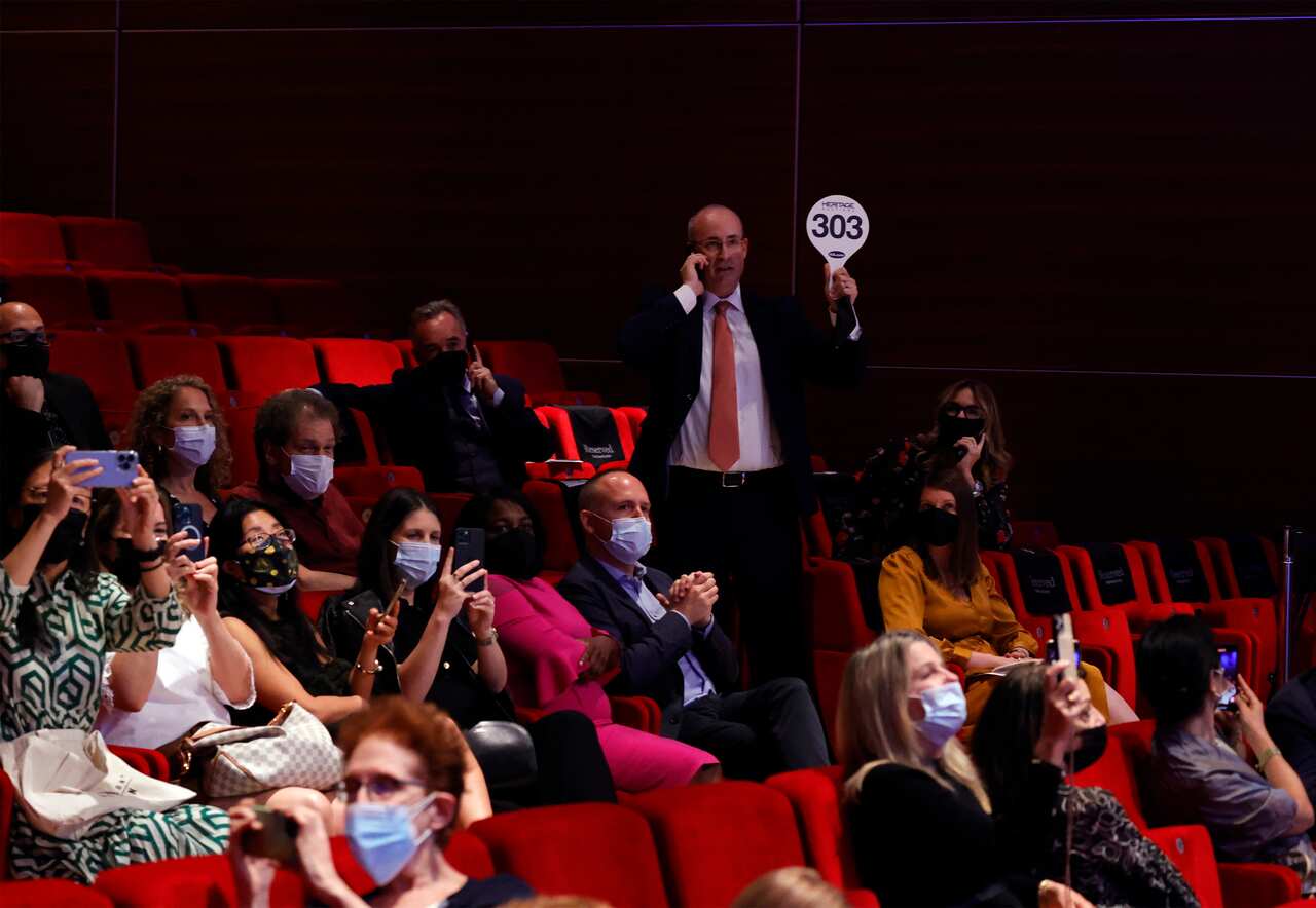 A bidder within a crowd holds up a paddle to signal their bid on the medal.
