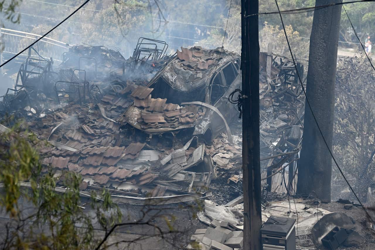 A burnt out car and the rubble of a home