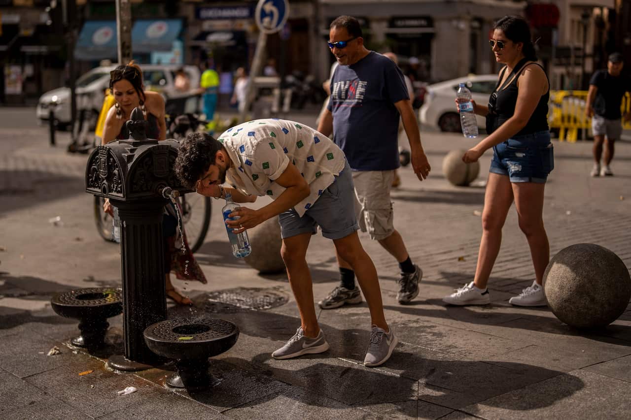 A man drinks from a public drinking fountain.