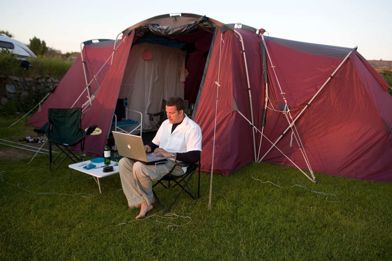 A man works at his laptop while camping.