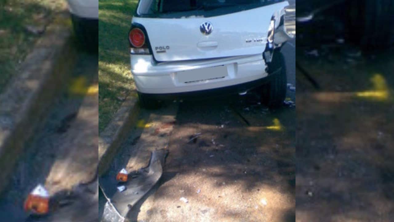 A white Volkswagen after an accident with scrap metal in the gutter and the right side of the car missing in the back