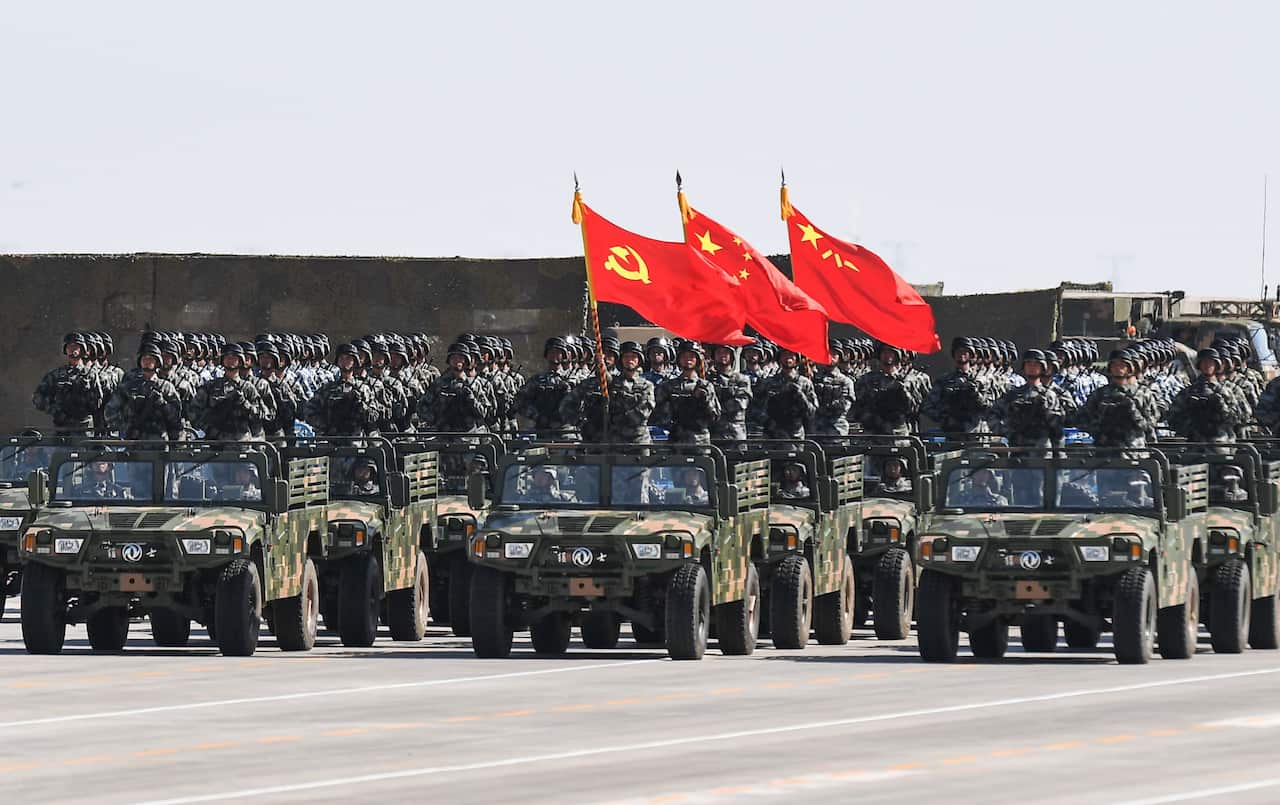 Chinese soldiers carry the flags of the Communist Party during a military parade.