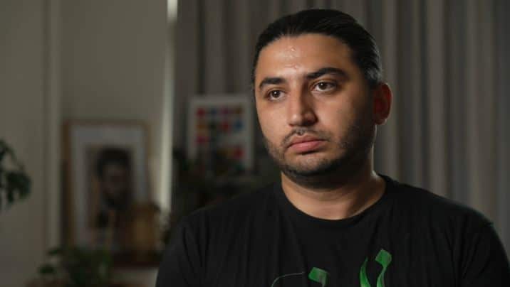 A man with black hair wearing a black t-shirt.