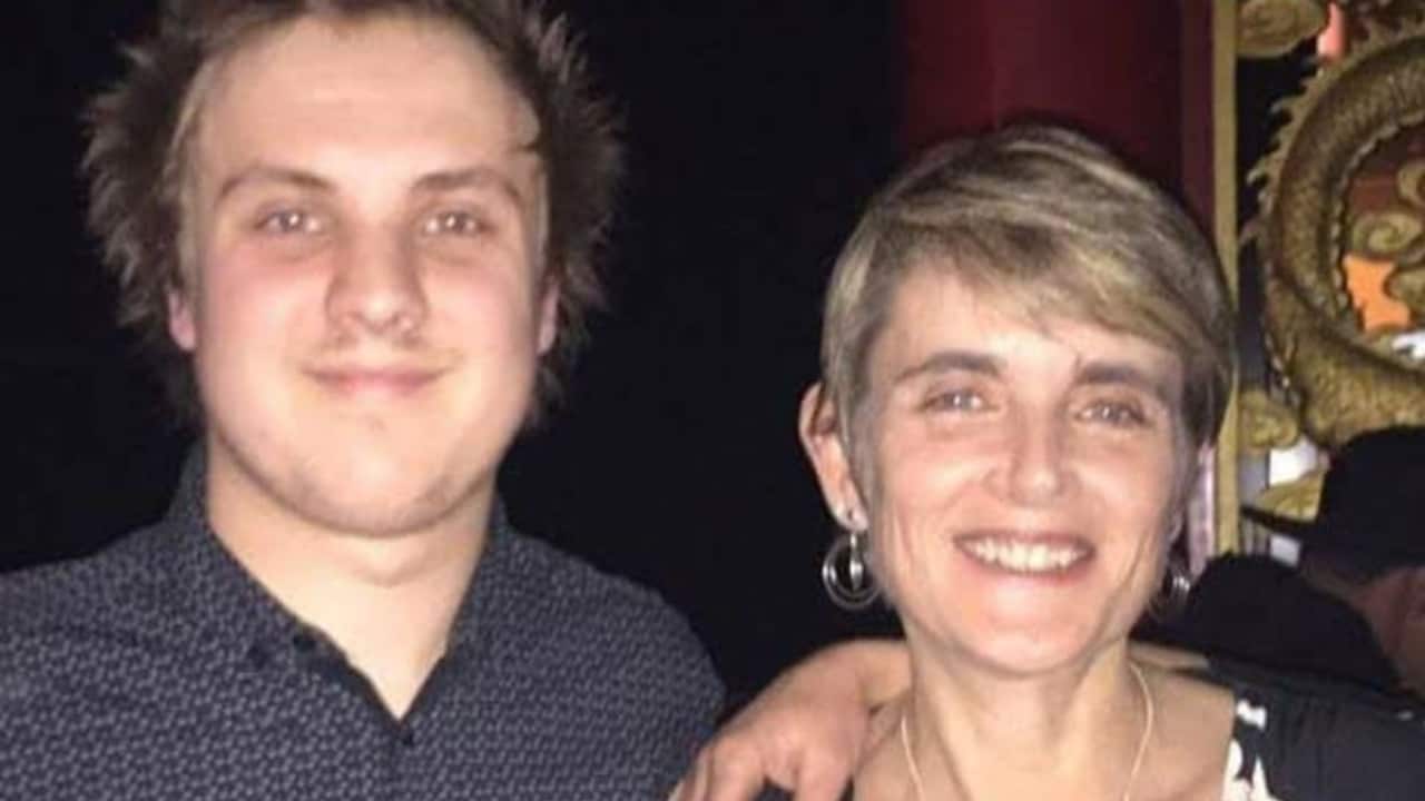 A young man with spiky hair smiles next to a middle aged woman with short hair