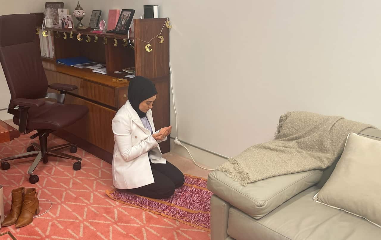 Fatima Payman kneels on a red prayer mat to pray in her office.