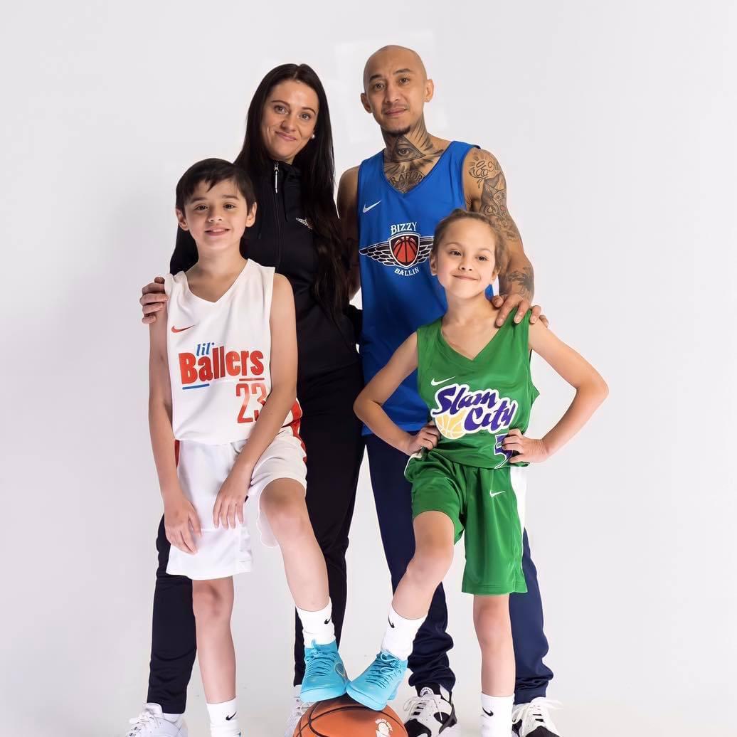 A boy and a girl stand with their parents behind them.