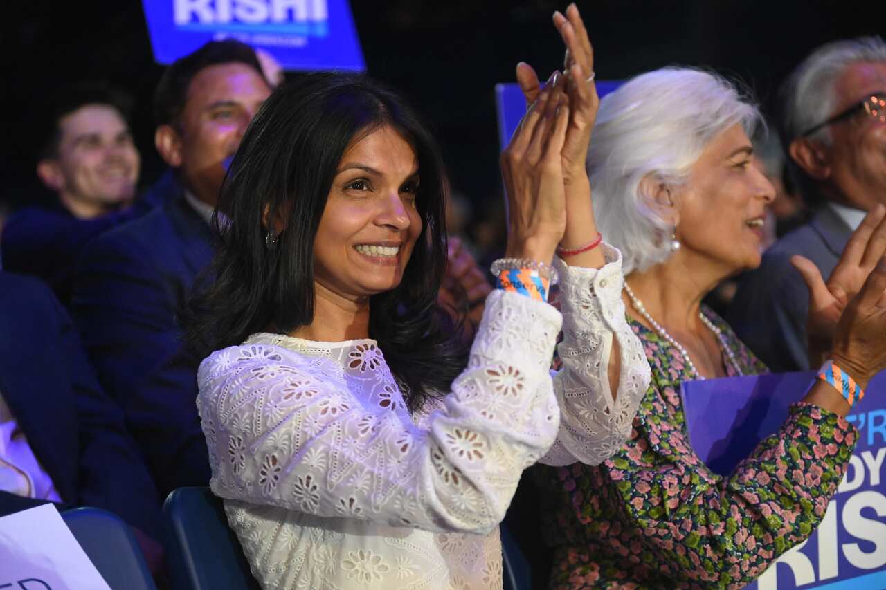 Akshata Murthy sitting in an audience clapping and smiling.