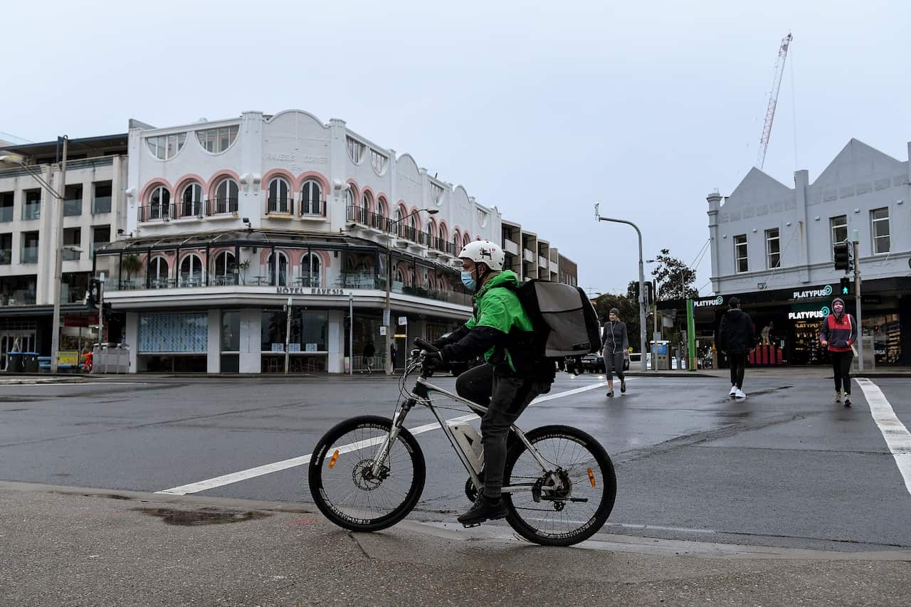 A food delivery worker riding a bicycle down a street.