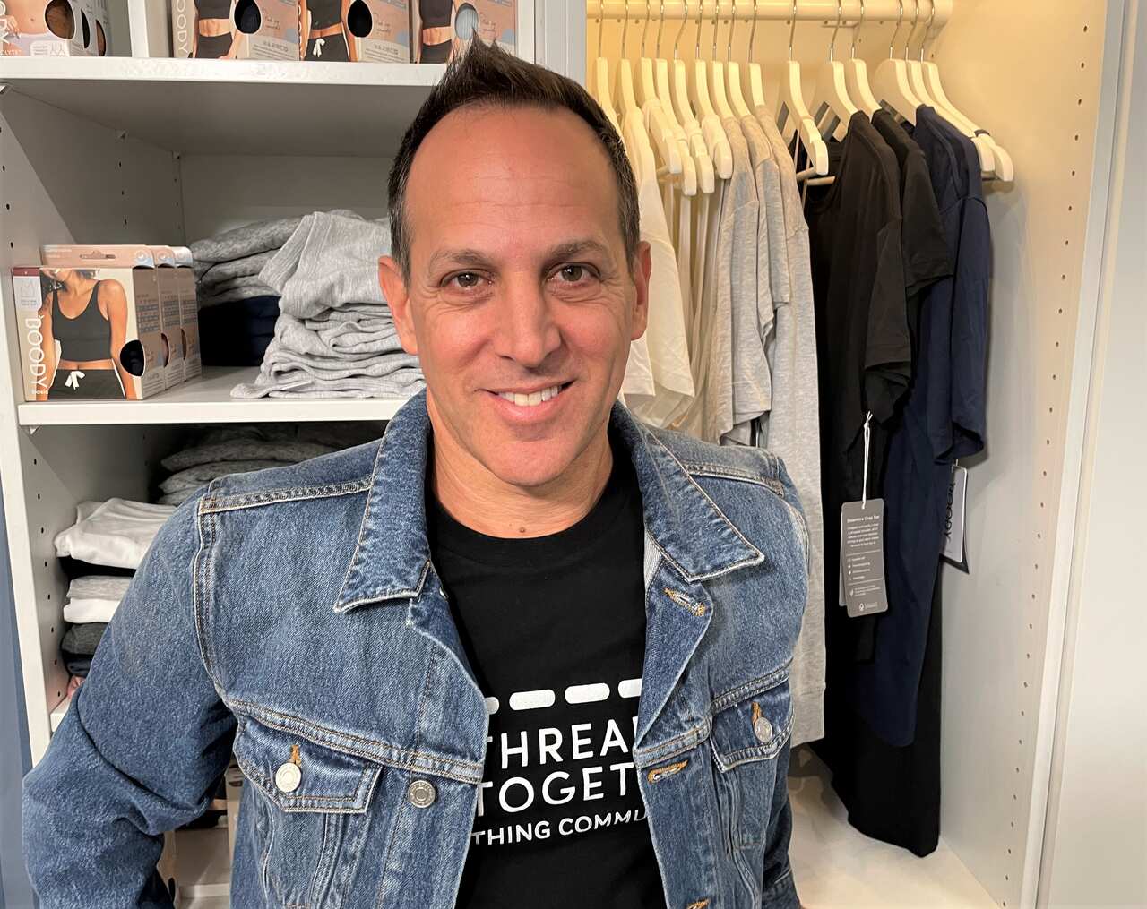 Thread Together CEO Anthony Chesler in front of a stocked wardrobe.