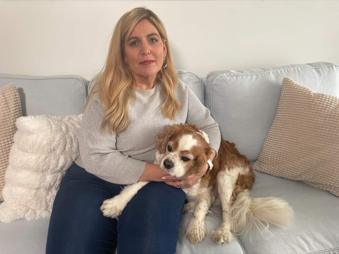 A lady on the couch with her dog.