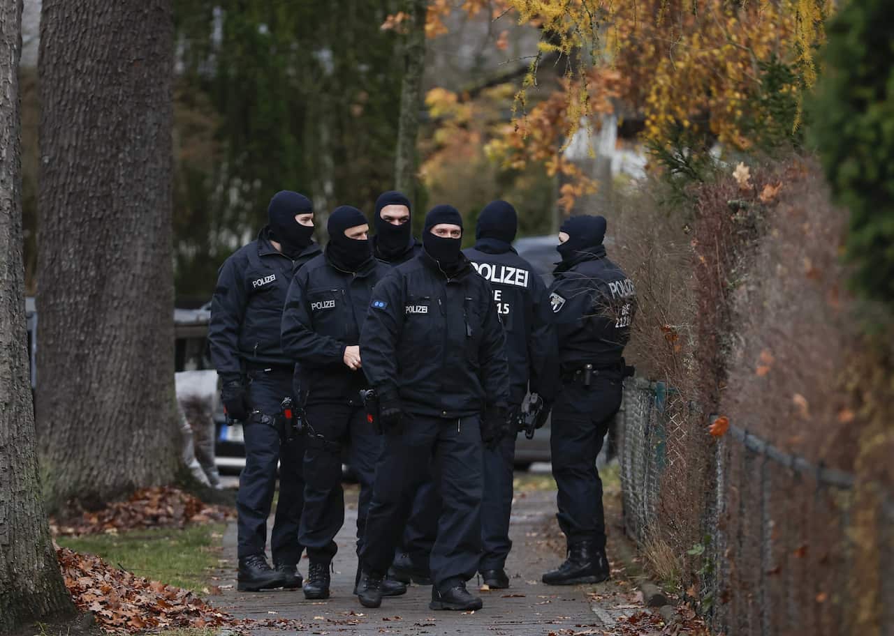 Men in police uniforms and balaclavas stand together.