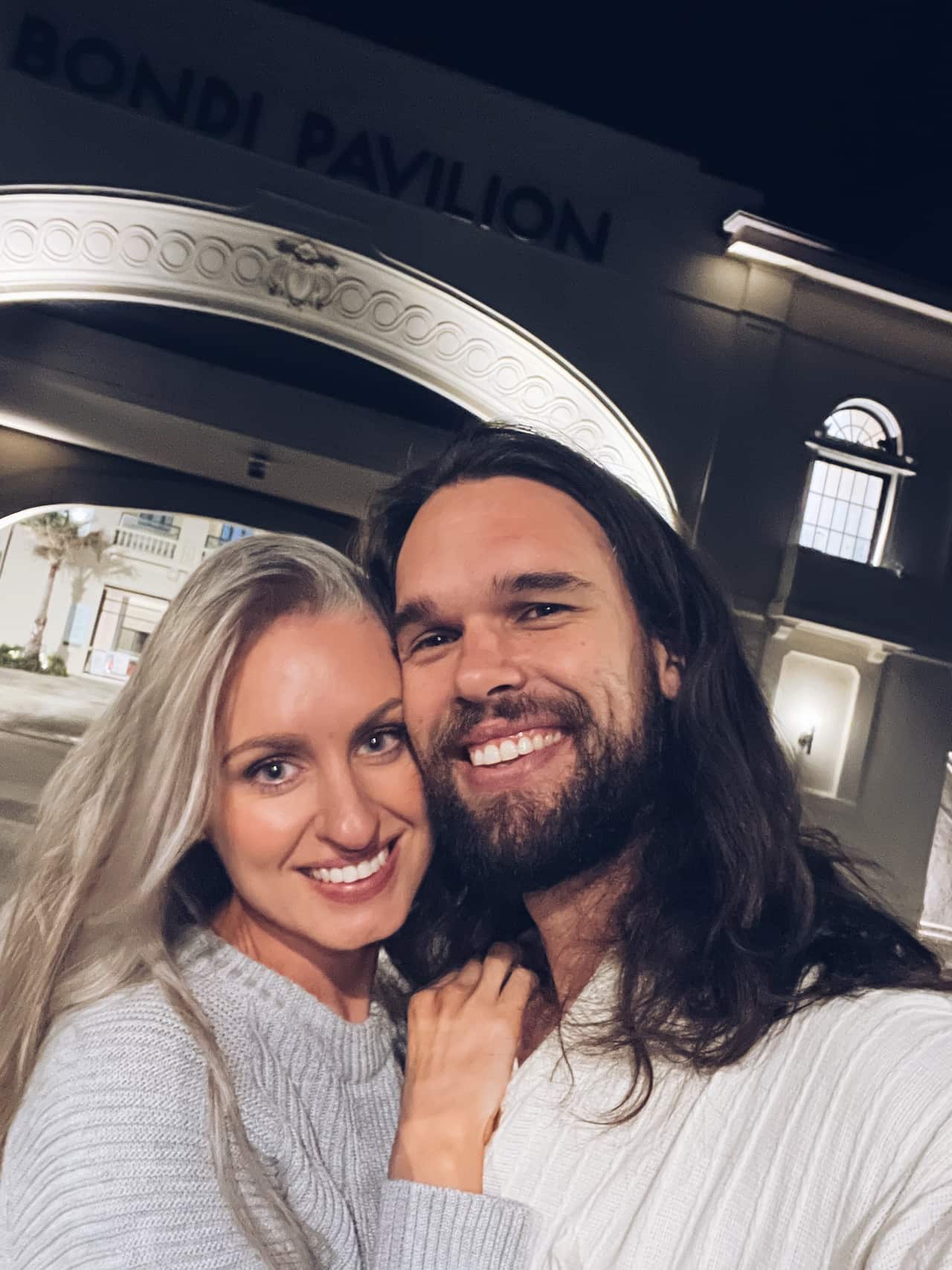  A happy couple share an embrace and smile at the camera.