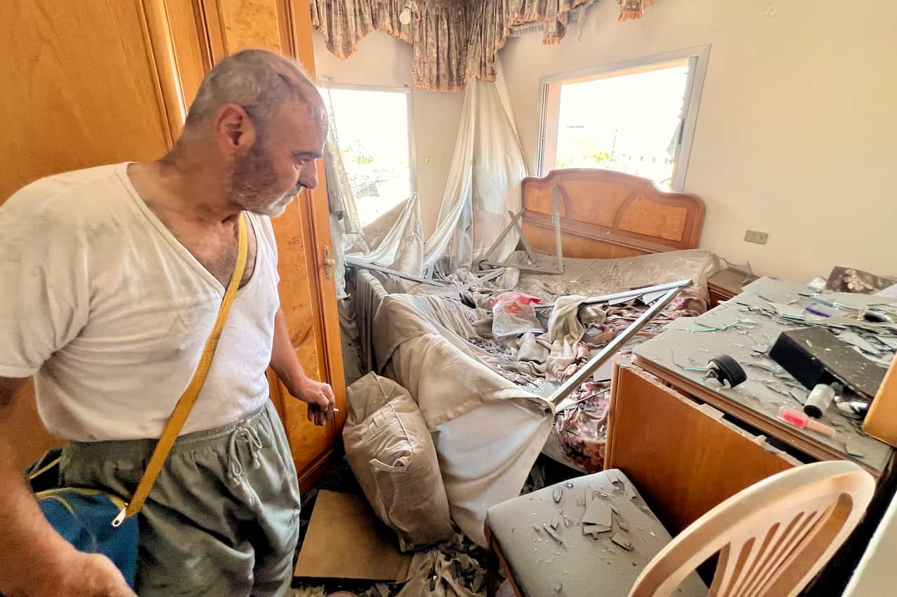 A man with a solemn expression on his face inspects his house following an airstrike.