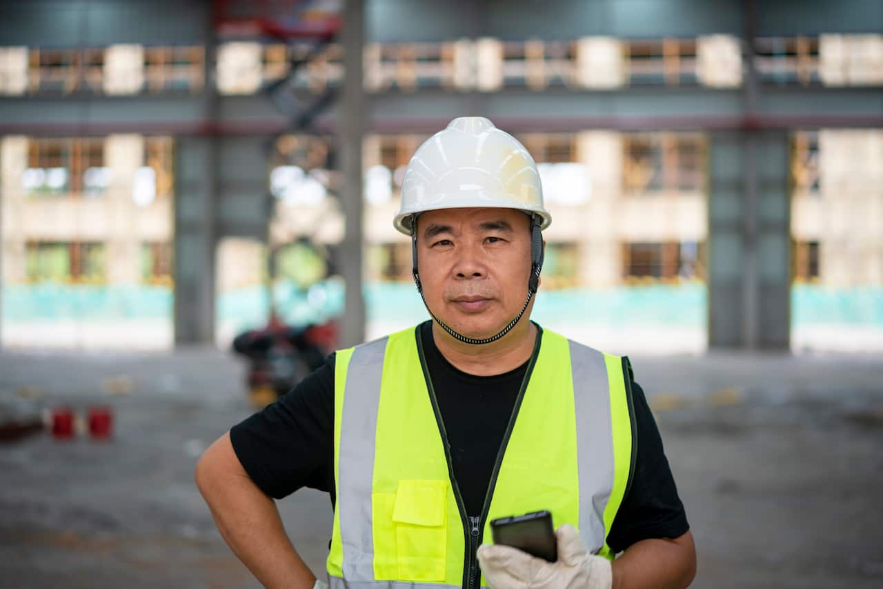 A male engineer holds a telephone at a construction site
