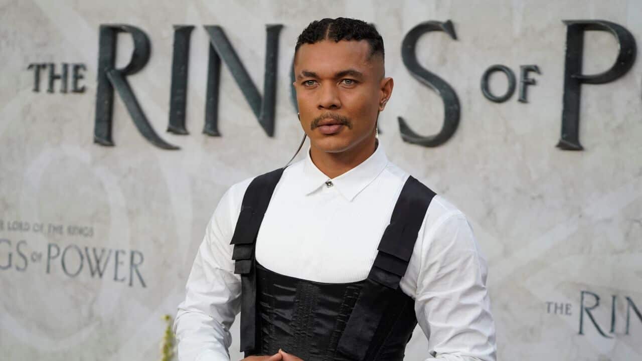 Ismael Cruz Cordova poses on the red carpet in front of a "Rings of power" banner