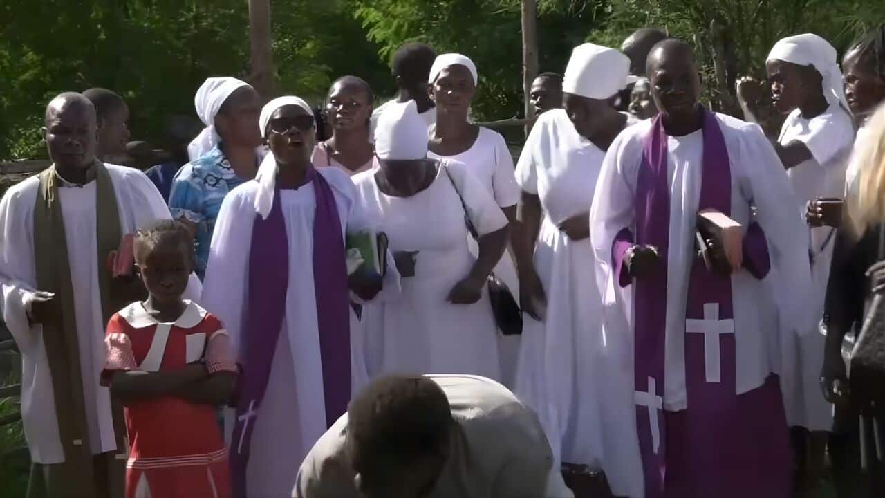 A group of African mourners in white gowns.