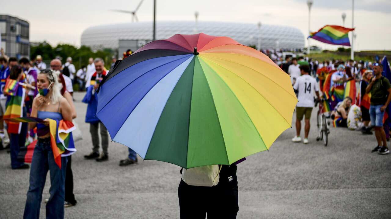 People wave rainbow flags in front of the Allianz Arena stadium in Munich, Germany