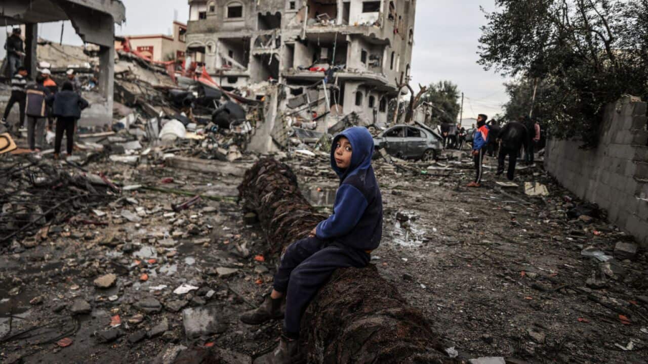 A boy sits on a fallen tree amid rubble after an air strike hit a refugee camp in Gaza