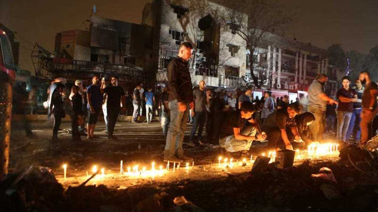 People light candles at the scene of a massive car bomb attack in Karada,