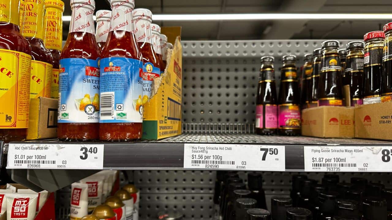 Supermarket shelves with chilli sauce bottles. There is an empty section where products are out of stock