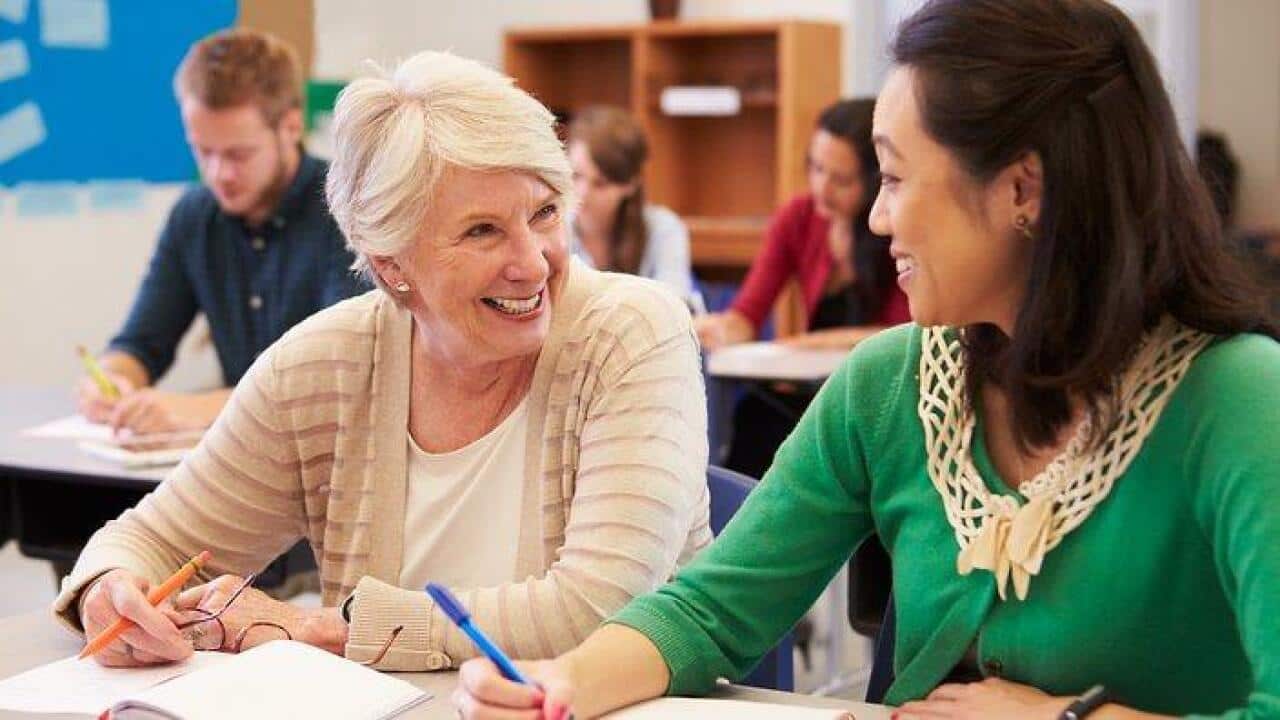 Teacher and student sit together at an adult education class