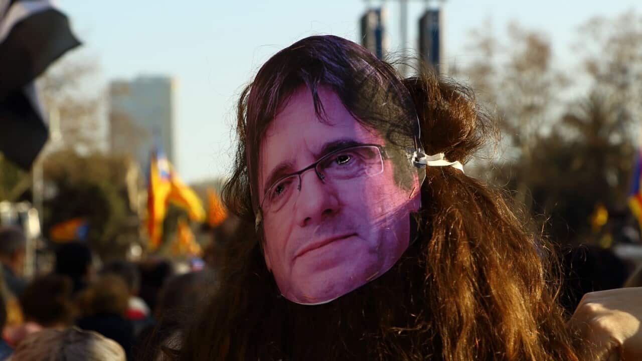 A protester wears a mask of ousted separatist president Carles Puigdemont during a demonstration in Barcelona.