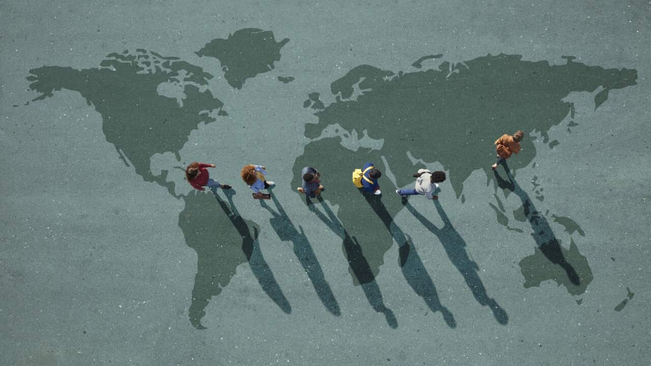 People walking in line across world map, painted on asphalt, front person walking left