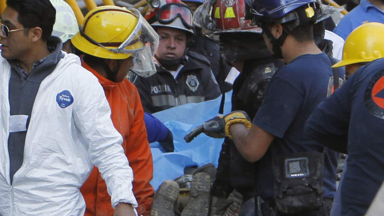 Rescuers carry a body of a worker after a building collapsed in Mexico