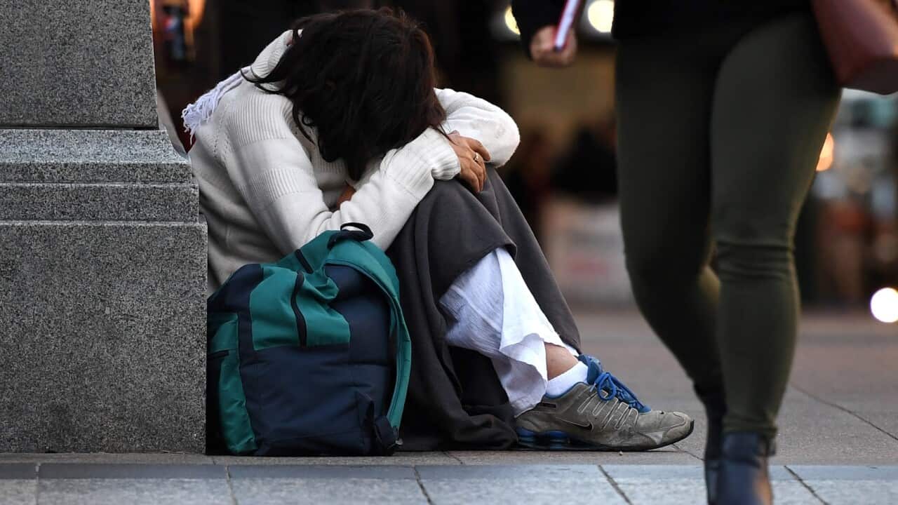 A homeless woman sits on a street corner in central Brisbane.