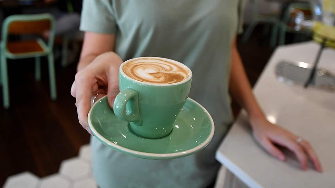 A waitress is seen holding a coffee at a cafe in Canberra