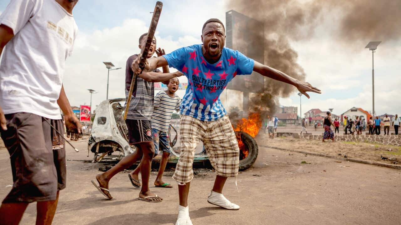 Demonstrators gather in front of a burning car during an opposition rally in Kinshasa on September 19, 2016.