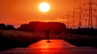 A person riding a bicycle underneath a very red sky.