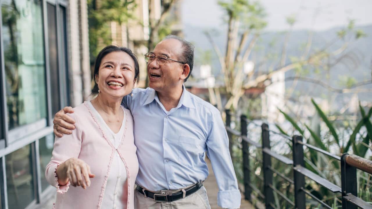 Happy senior couple standing on balcony at home