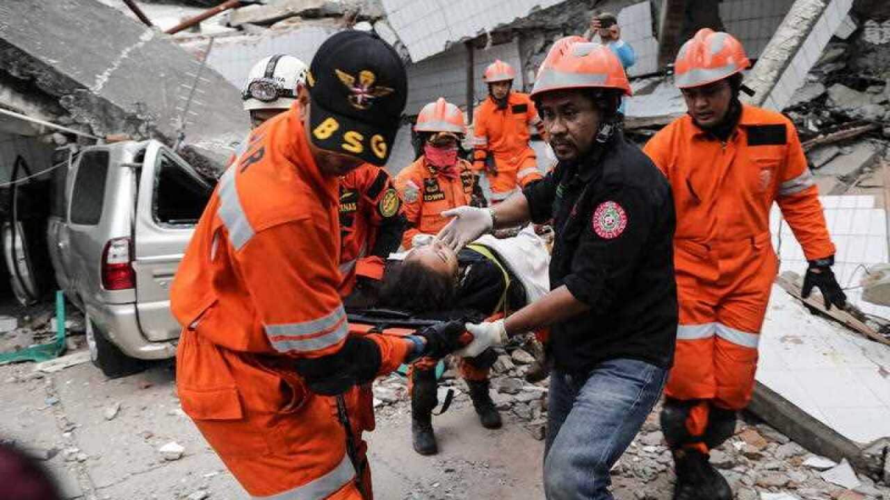 Indonesian rescuers evacuate a survivor from under a collapsed restaurant building in Palu, Central Sulawesi, Indonesia, 30 September 2018.