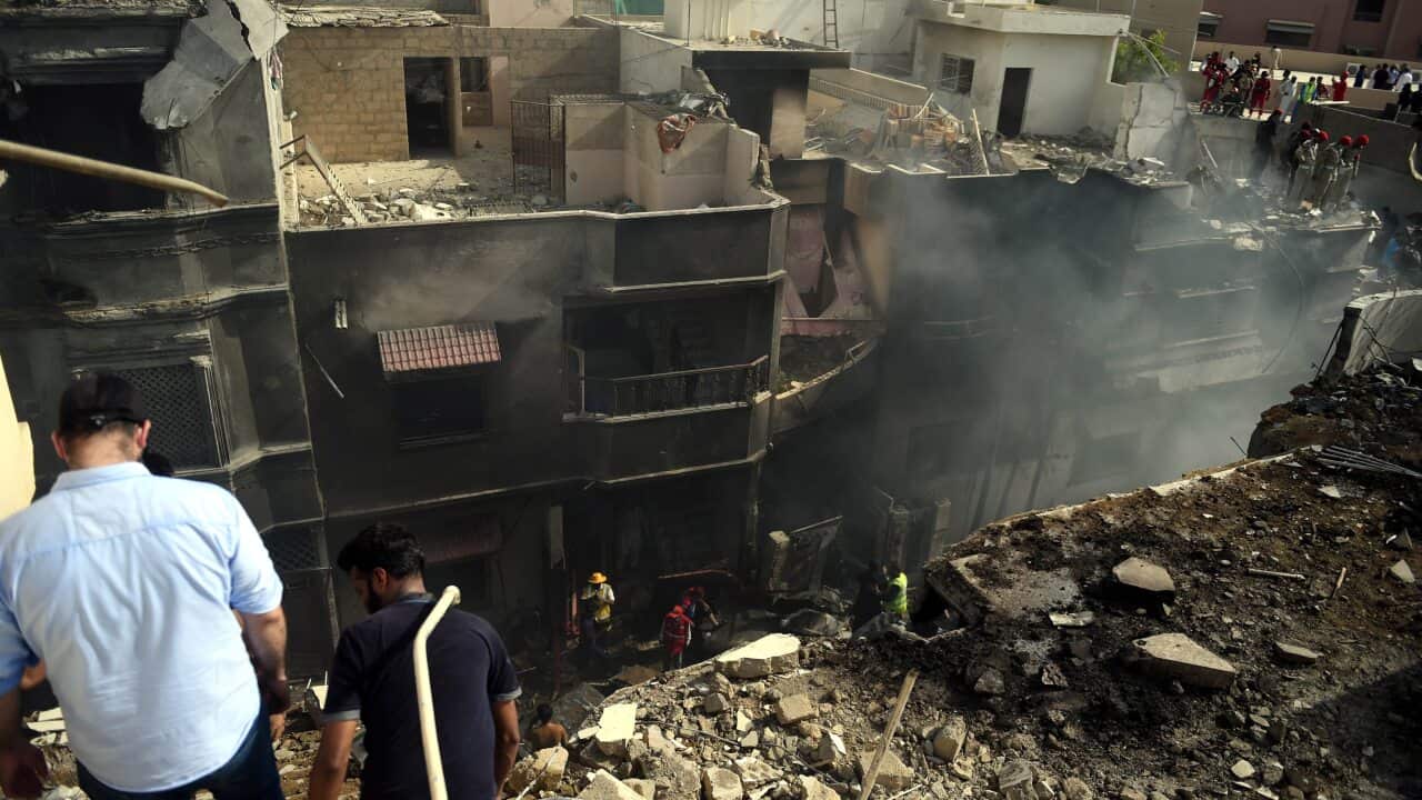 Locals inspect the destruction caused after a passenger plane crashed on a residential colony, in Karachi, Pakistan.