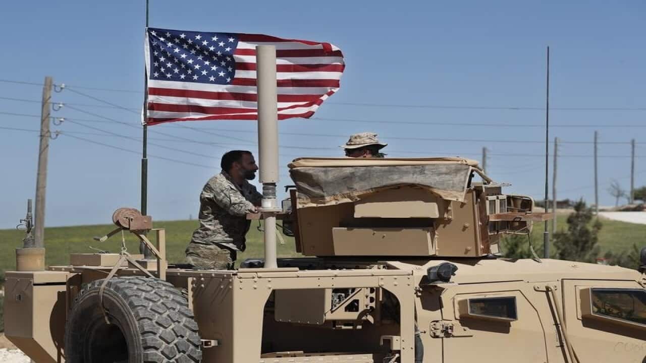 A Syrian Democratic Forces soldier speaks with a US soldier