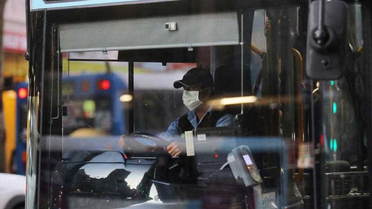 A bus driver wears a face mask while driving a public bus in Sydney.