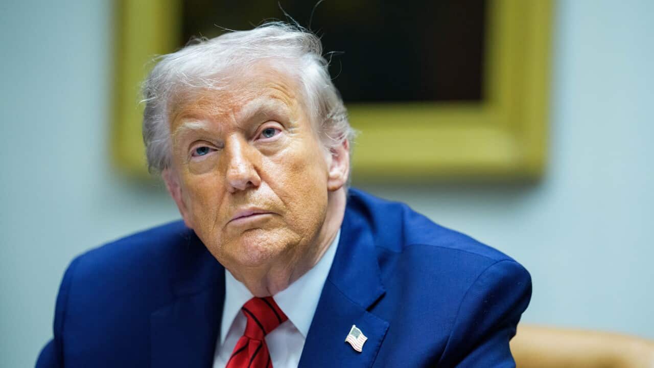 Donald Trump in a blue suit and a red tie is sitting.