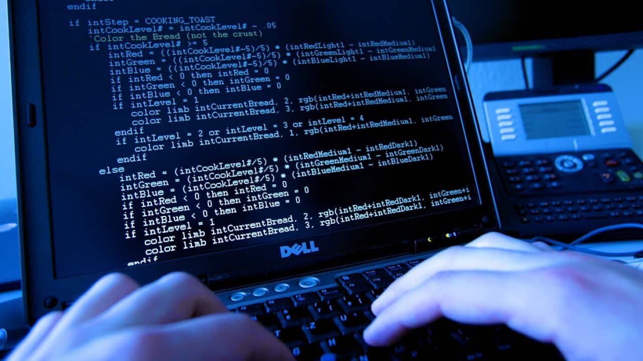 The hands of a person operating a computer keyboard and the computer monitor.