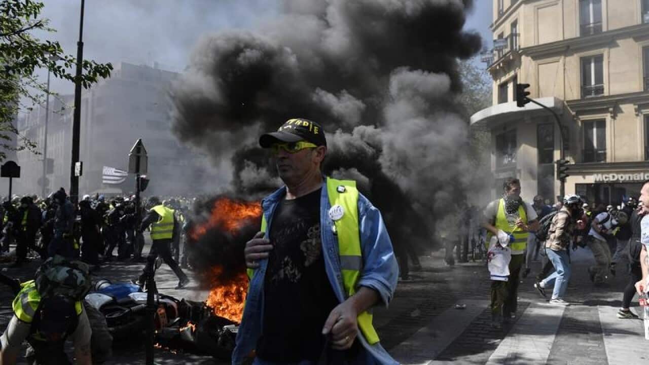 Protesters run from the police after setting a street fire