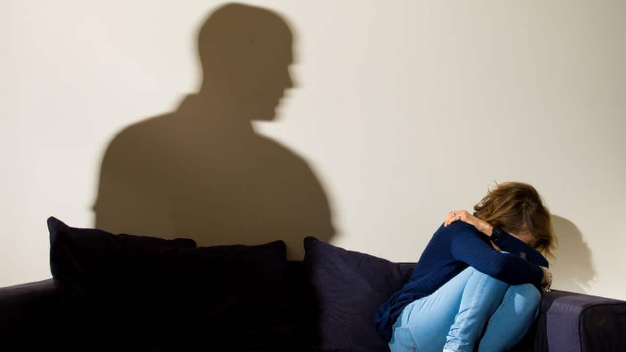 A woman cowers in the corner affected by domestic violence