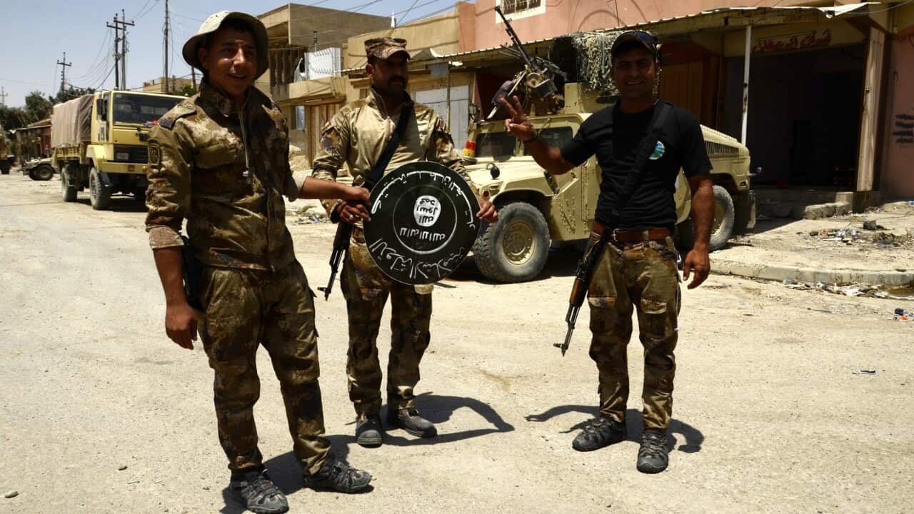 Iraqi Army soldiers hold a flag belonging to the Islamic State in the formerly IS held district of Shifaa, western Mosul, Iraq, 17 June.