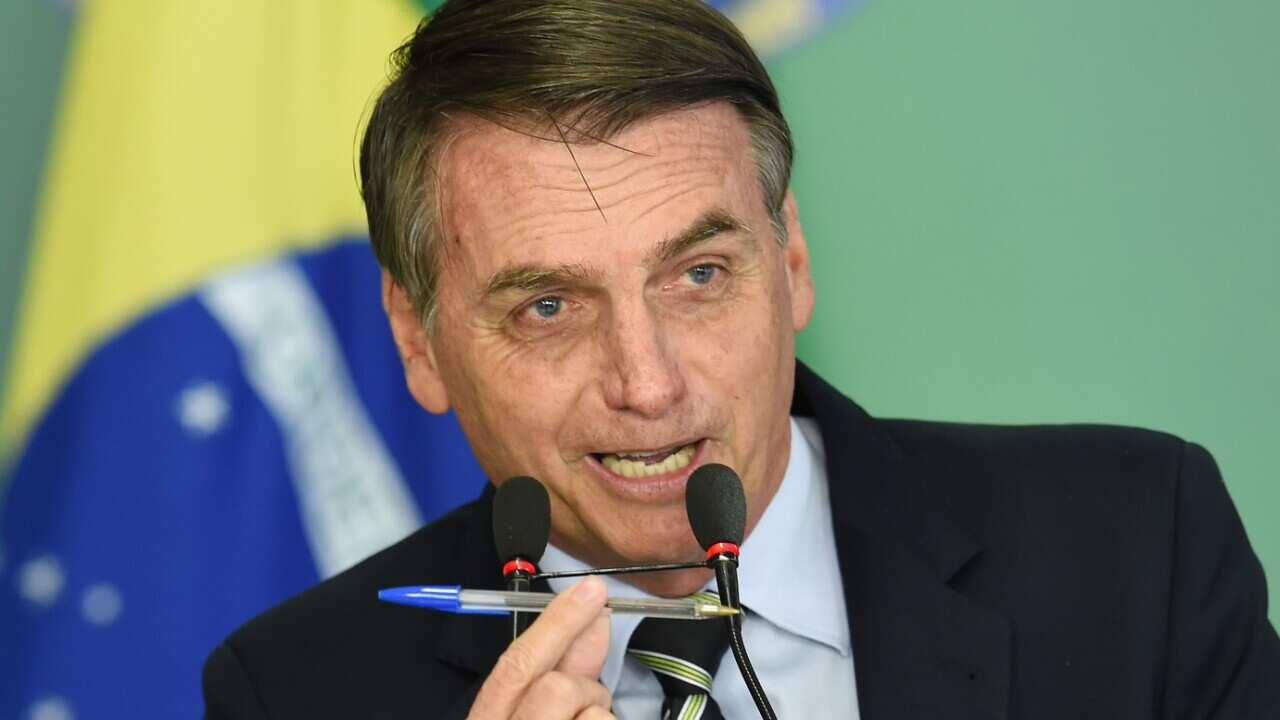 Brazilian President Jair Bolsonaro delivers a speech and shows a popular pen during a signing ceremony